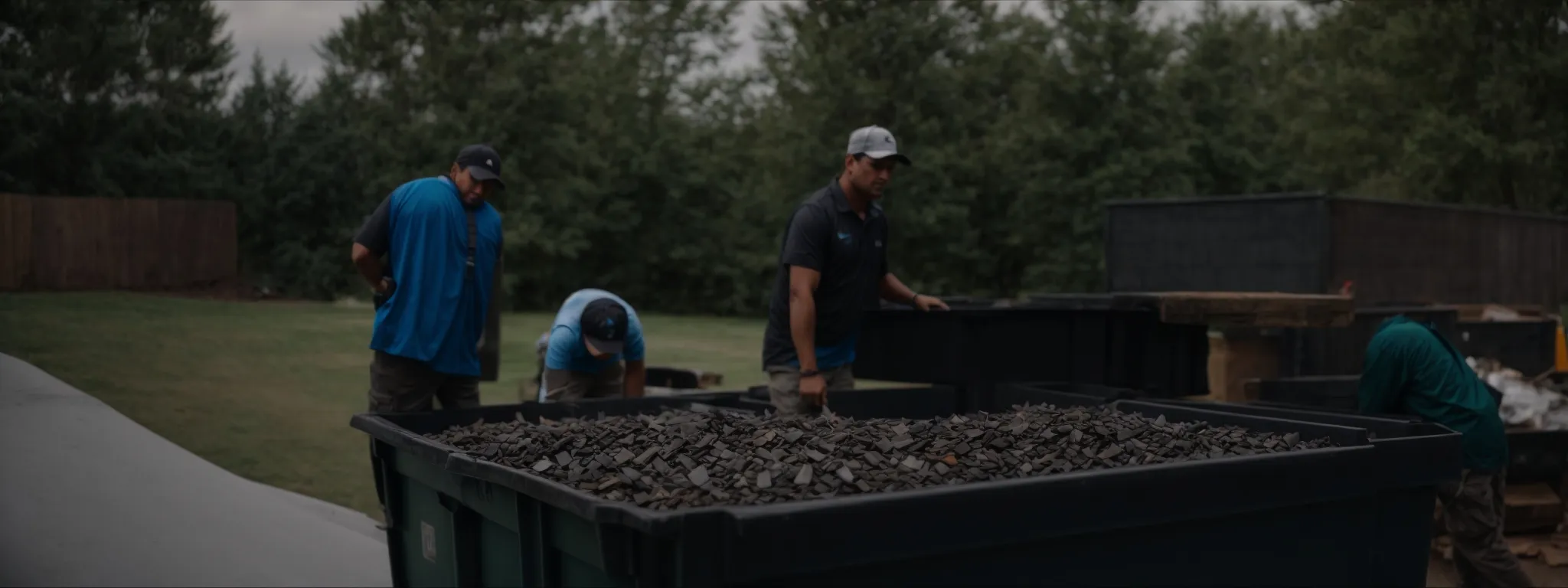 a group of roofing professionals places old shingles into a dedicated dumpster for proper disposal.